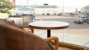 A view from a window with a round table and chairs, overlooking a waterfront area with boats and a pier. - Bowa Hotel (Magong)