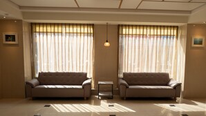 A spacious room with two sofas facing each other, a small table, and a hanging light fixture. - Bowa Hotel (Magong)