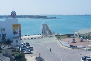 A coastal area with a pier extending into the sea, a parking lot, and a building with a cafe sign. - Bowa Hotel (Magong)