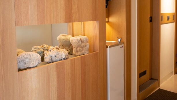 A wooden reception desk with a white refrigerator and a framed picture on the wall. - Bowa Hotel (Magong)
