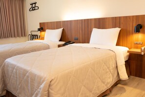 A hotel room with two beds, wooden headboards, bedside lamps, and a telephone on the nightstand. - Bowa Hotel (Magong)