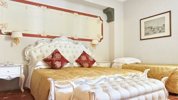 A bedroom with a large bed, two bedside tables, and a framed picture on the wall. - Villa Royal (Florence)
