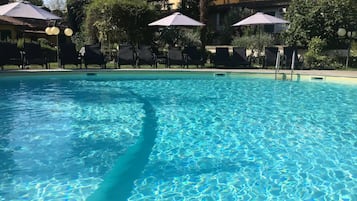 Una piscina al aire libre de temporada, sombrillas