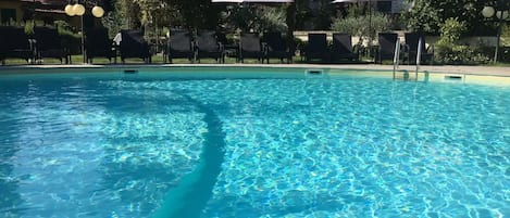 Una piscina al aire libre de temporada, sombrillas, tumbonas