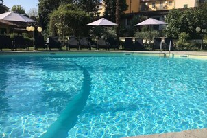 Een seizoensgebonden buitenzwembad, parasols voor strand/zwembad