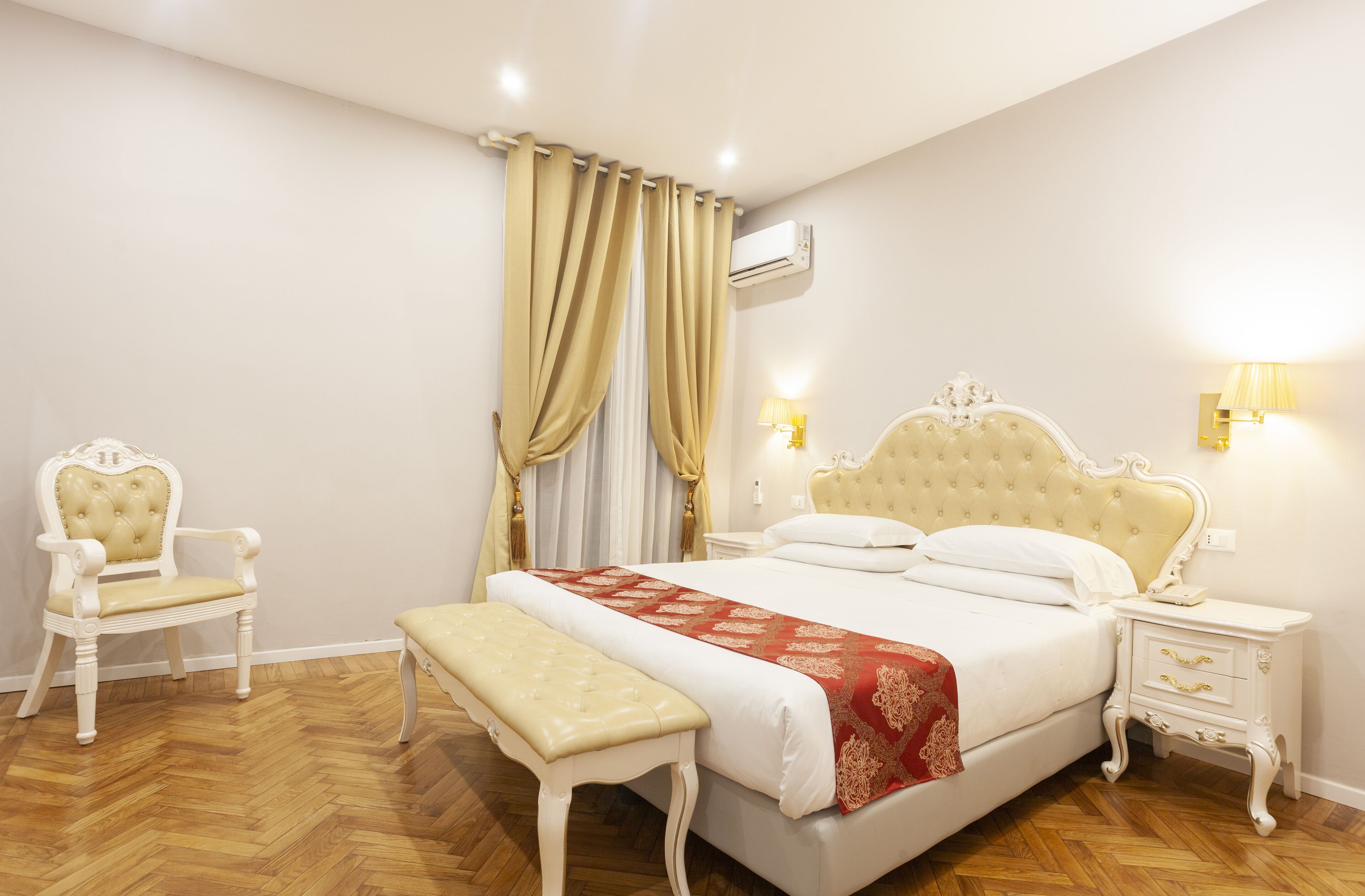 A bedroom with a large bed, a chair, a bench, and a nightstand.