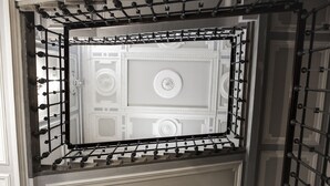 A view through a metal railing of a room with ornate ceiling details and a circular central medallion. - Villa Royal (Florence)