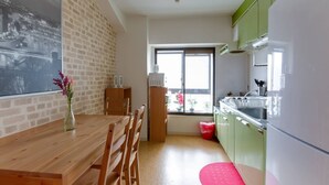 Une cuisine avec une table en bois, des chaises, une fenêtre et des armoires vertes.
