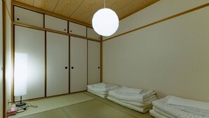 Une pièce de style japonais traditionnel, avec un sol recouvert de tatamis, une porte coulissante en papier de riz (shoji) et un luminaire suspendu.