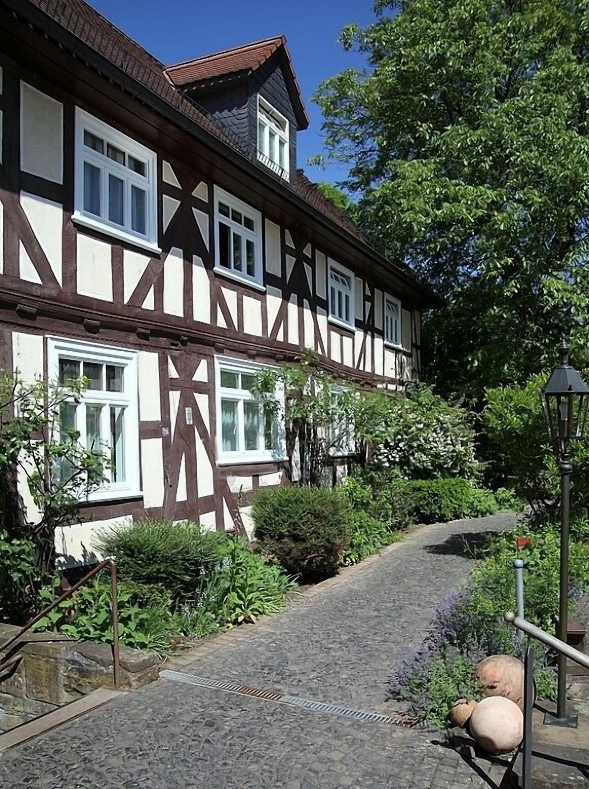 Une maison traditionnelle à colombages, avec un chemin pavé menant à l’entrée.