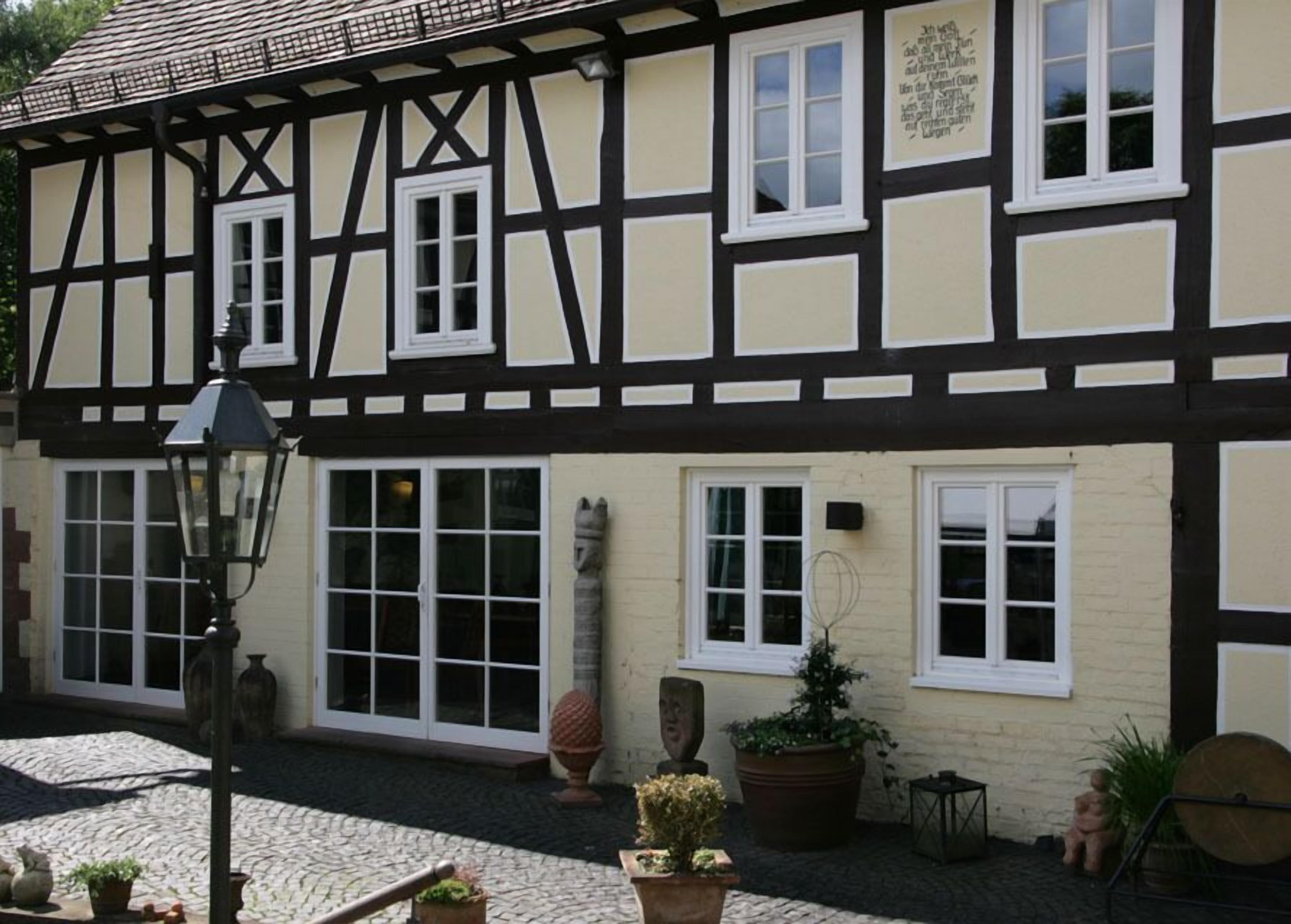 Un bâtiment traditionnel à colombages, doté de nombreuses fenêtres et bordé d’un chemin pavé.
