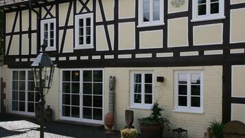 Un bâtiment traditionnel à colombages, doté de nombreuses fenêtres et bordé d’un chemin pavé.