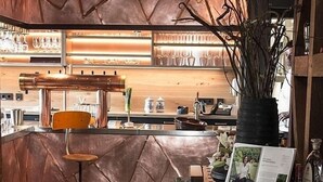 Un espace bar avec un comptoir en bois, des tabourets et un présentoir à menus.