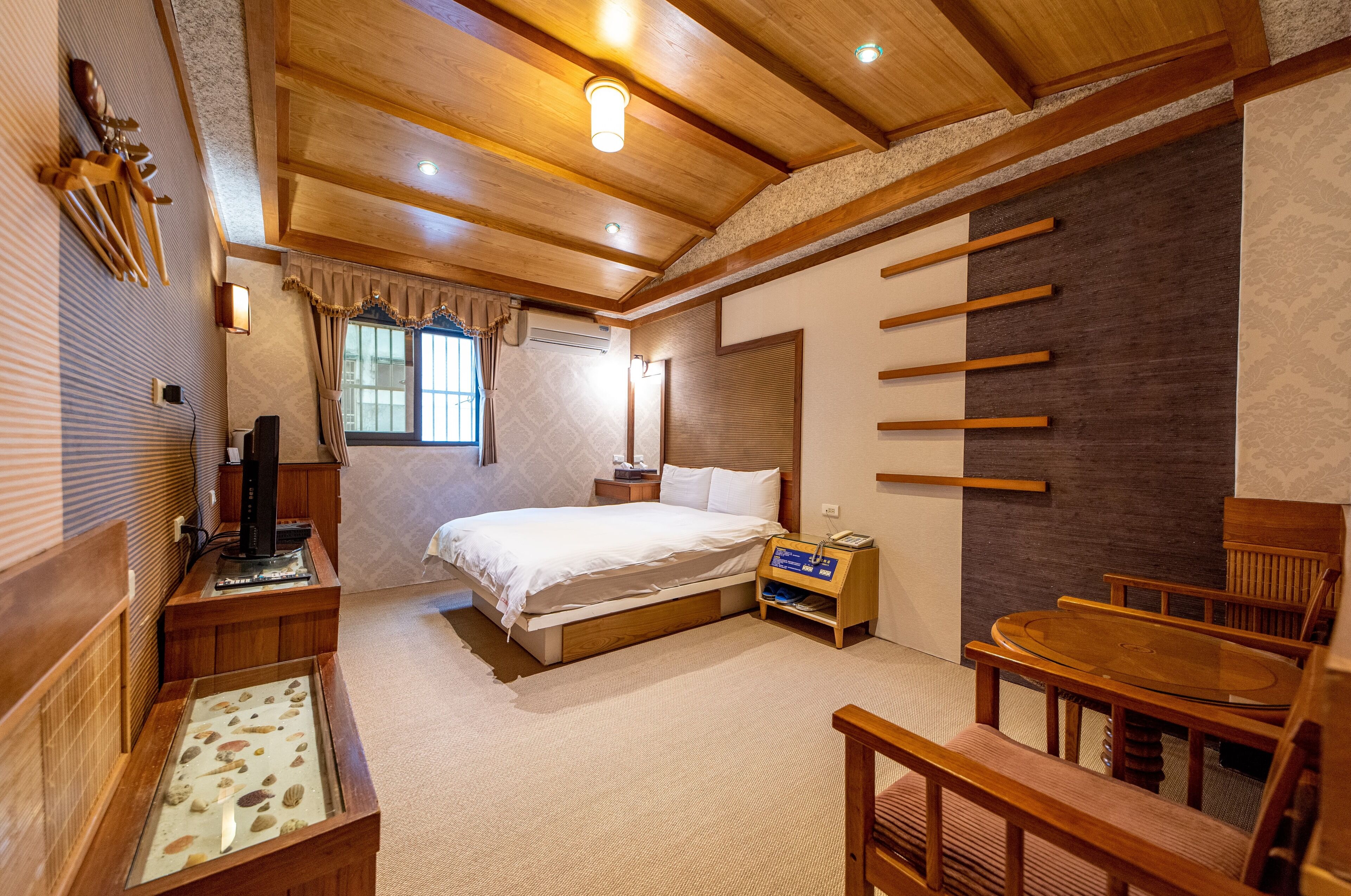 Ein Schlafzimmer mit Bett, Nachttisch, Fernseher und einem kleinen Holztisch mit einem dekorativen Gegenstand.