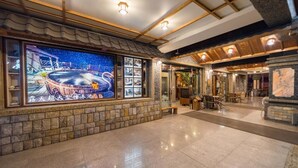 A spacious lobby with a large aquarium, stone walls, and a wooden ceiling. - Shankou Hotspring Hotel (Jiaoxi)