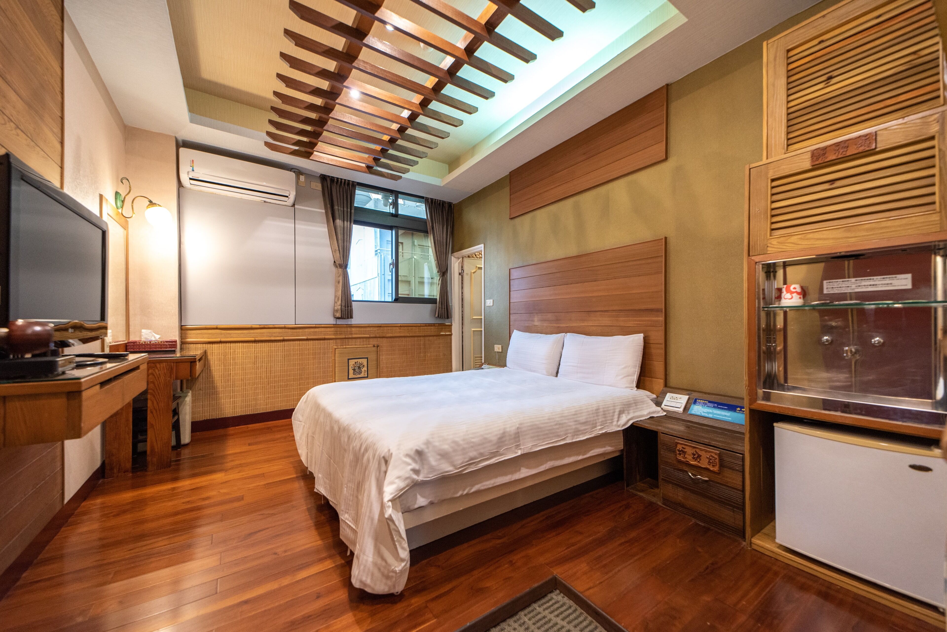 Una habitación de hotel con cama, escritorio, televisión y minibar.