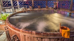 A hot spring bath with a wooden tub, a wooden bucket, and a stone wall with a starry pattern. - Shankou Hotspring Hotel (Jiaoxi)