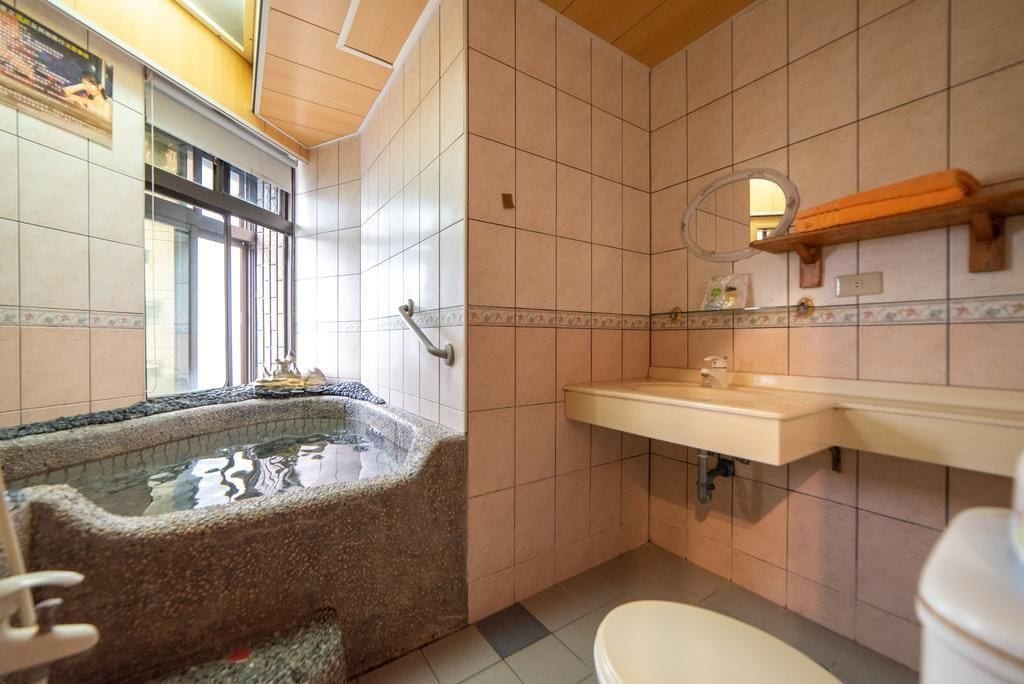 Une salle de bain avec un bain à remous en pierre, un lavabo et des toilettes.