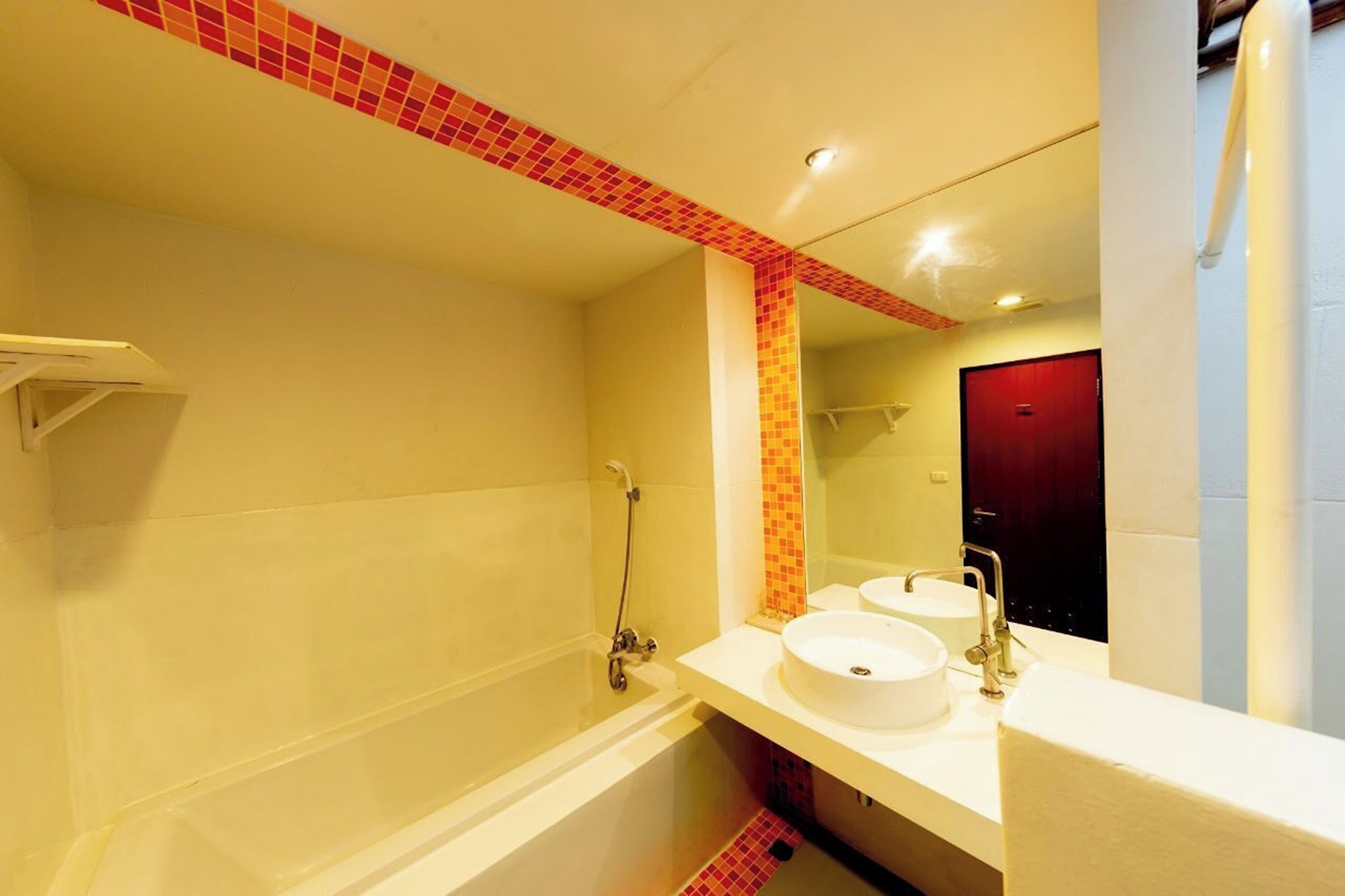 A bathroom with a bathtub, two sinks, and a red-tiled shower area.