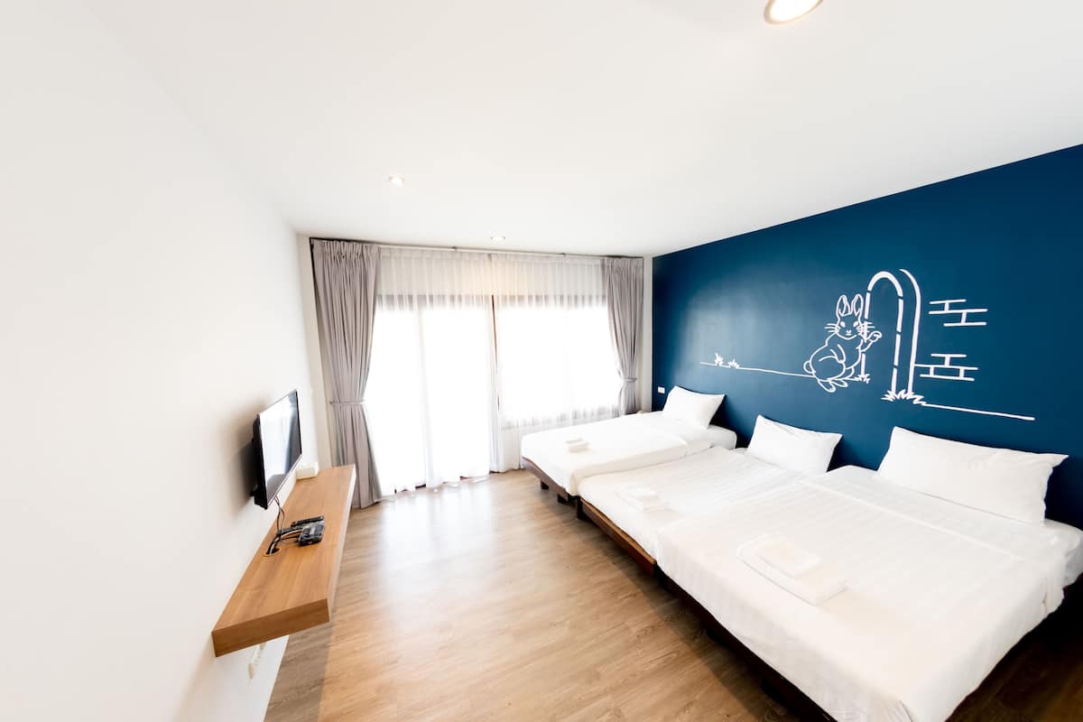 Habitación de hotel con una cama grande, un televisor en un estante de madera y una pared con un diseño decorativo.