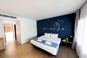 A hotel room with a bed, a night sky mural, a wooden floor, and a nightstand with a plant and phone. - Kochira (Hua Hin)
