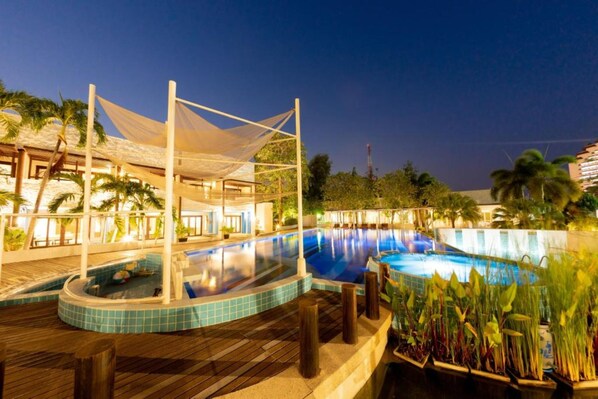 A swimming pool area with a wooden deck, a covered seating area, and a view of the surrounding landscape. - Kochira (Hua Hin)
