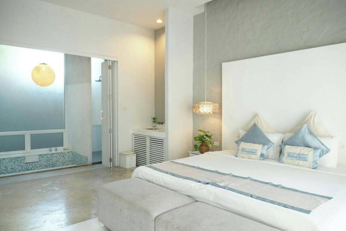 Un dormitorio moderno con una cama grande, una mesita de noche, una lámpara colgante y vistas al exterior.