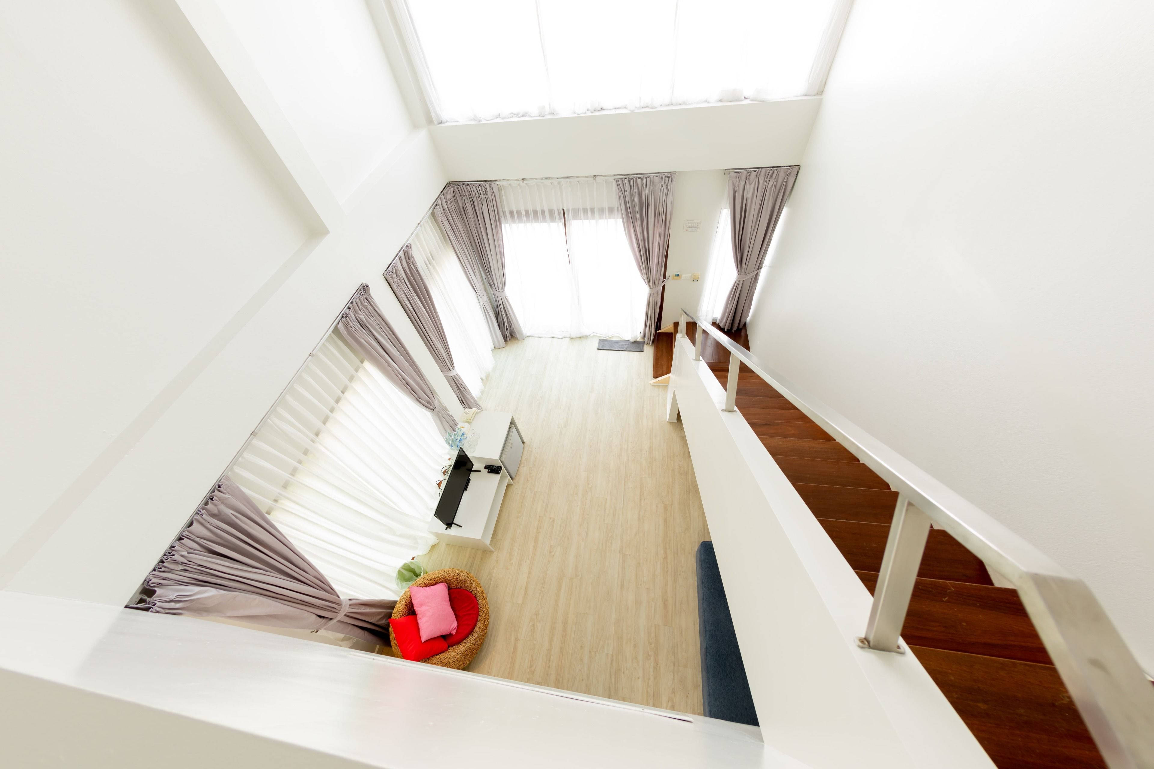 A modern interior with a staircase, a wooden floor, and a seating area with cushions.