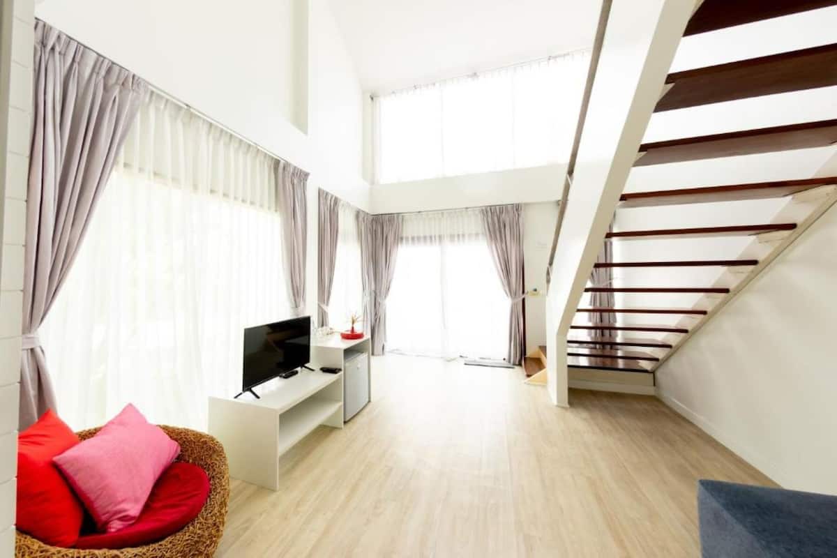 Una sala de estar moderna con una televisión de pantalla plana, un sofá y una escalera.