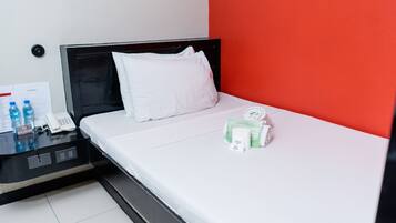 Una habitación de hotel con cama, escritorio y teléfono, y una pared roja.