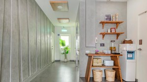 A modern hotel corridor with a wooden bench, a refrigerator, and a potted plant. - Chin Style Easy Stay (Magong)