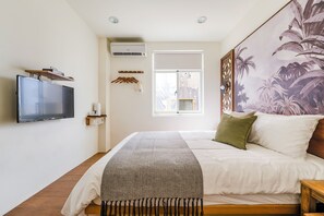 A bedroom with a bed, a television mounted on the wall, a window, and a wall-mounted air conditioner. - Chin Style Easy Stay (Magong)
