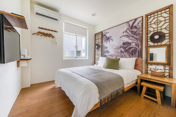 A bedroom with a bed, wooden floor, a window, a wall-mounted air conditioner, a coat rack, and a decorative panel with a palm tree painting. - Chin Style Easy Stay (Magong)