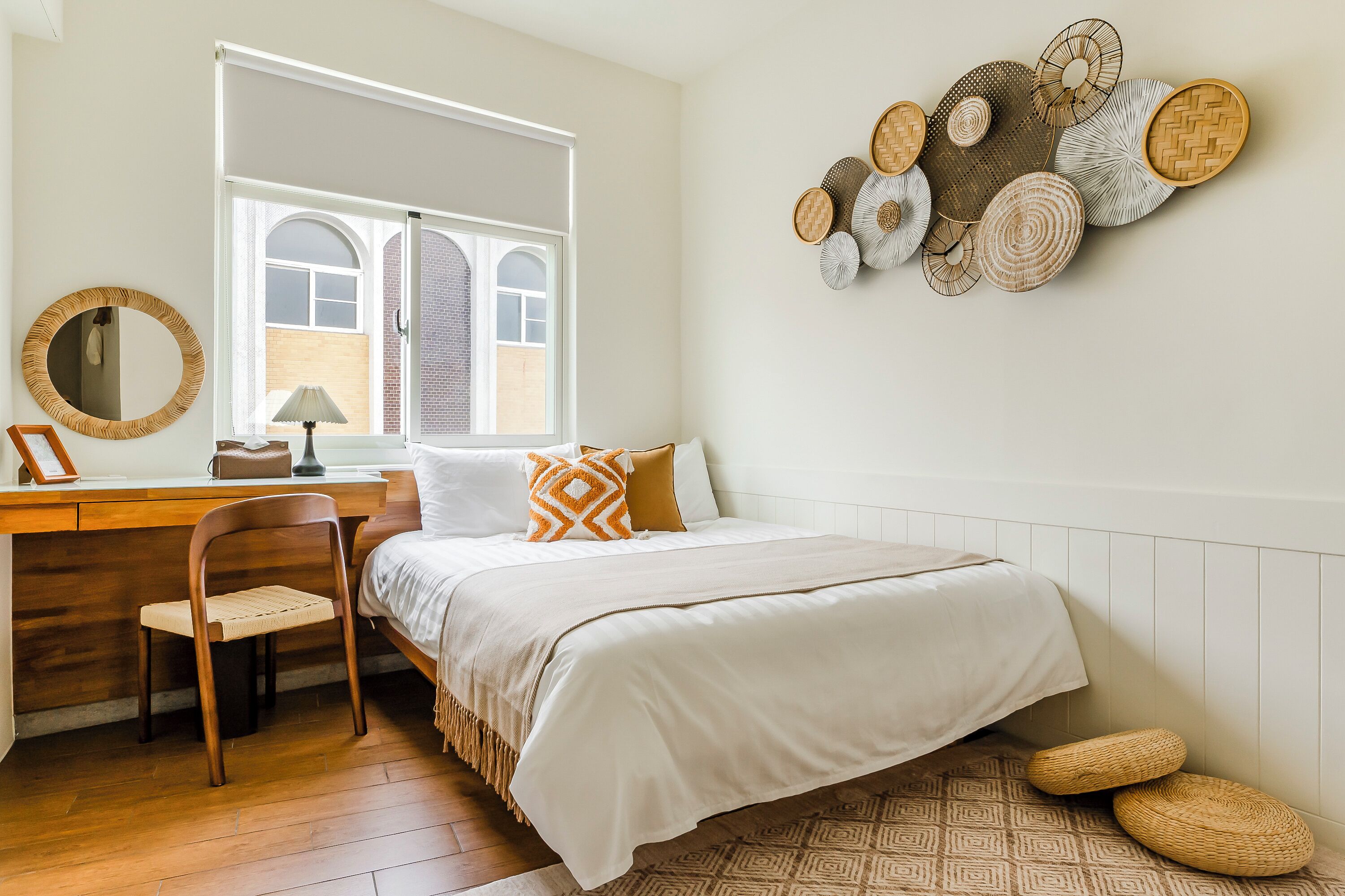 Een slaapkamer met een bed, een bureau, een stoel, een raam en een decoratie aan de muur.