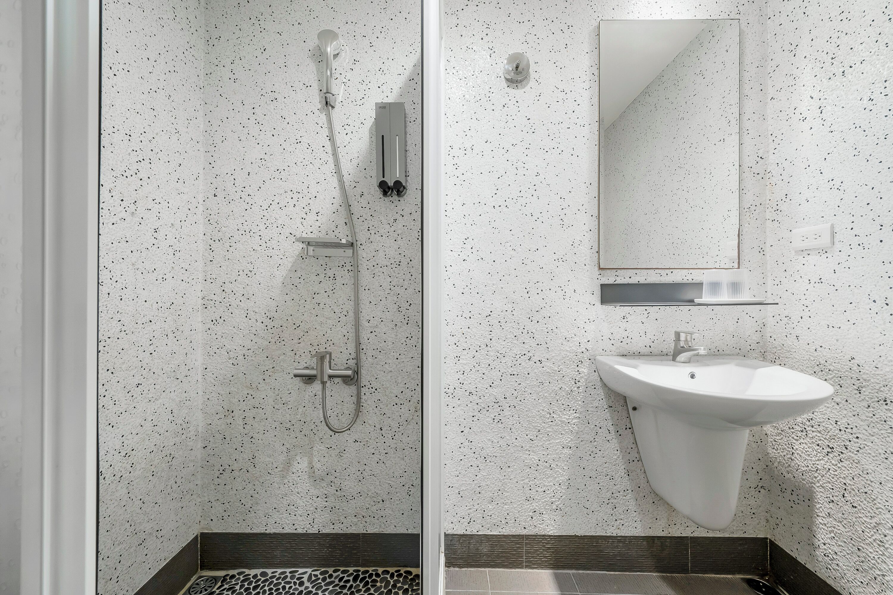 A modern bathroom with a shower, a sink, and a mirror.