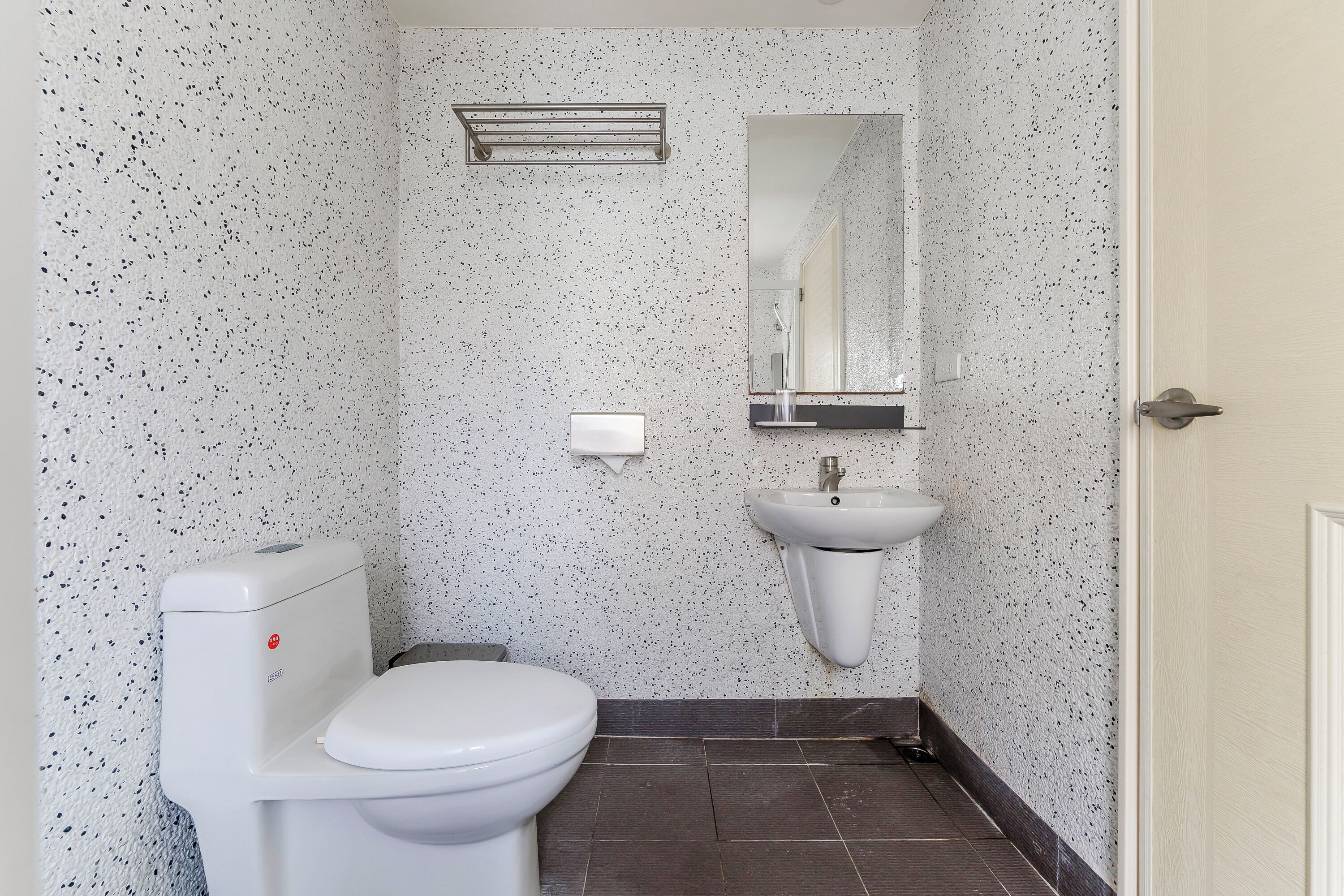 Et lille badeværelse med toilet, vask og spejl.
