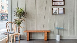 A wooden bench, a chair, a small table, and a potted plant in a room with a concrete wall and tiled floor. - Chin Style Easy Stay (Magong)
