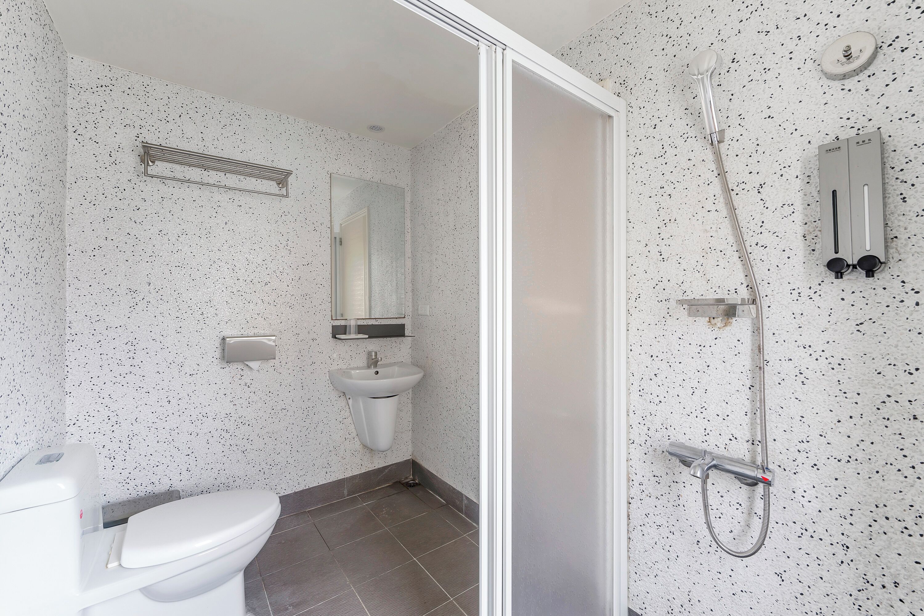 A modern bathroom with a toilet, sink, mirror, and shower.