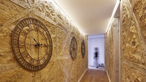 A hallway with large wall-mounted clocks, wooden flooring, and a door leading to another room. - Sonel Investe Apartments Madalena 287 Studios (Lisbon)