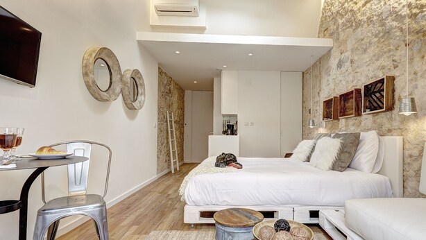 A modern bedroom with a large bed, a desk with a chair, and a dining area with a table and chairs. - Sonel Investe Apartments Madalena 287 Studios (Lisbon)