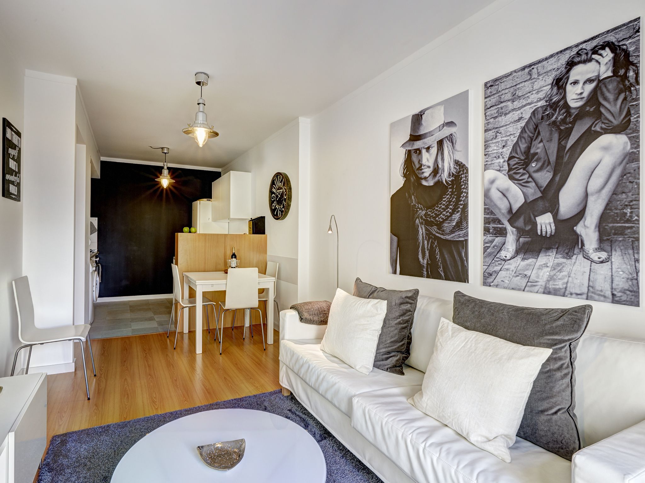 Un salon moderne avec un canapé blanc, une table à manger et un coin cuisine à l’arrière-plan.