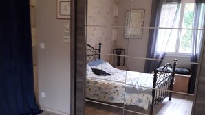 Ein Schlafzimmer mit Bett, Stuhl und Spiegel.