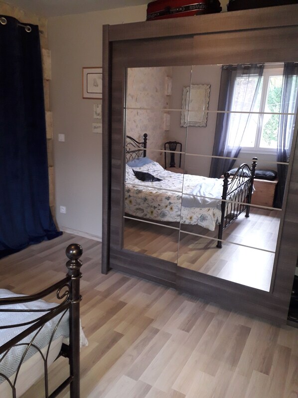 A bedroom with a bed, a chair, and a mirror.