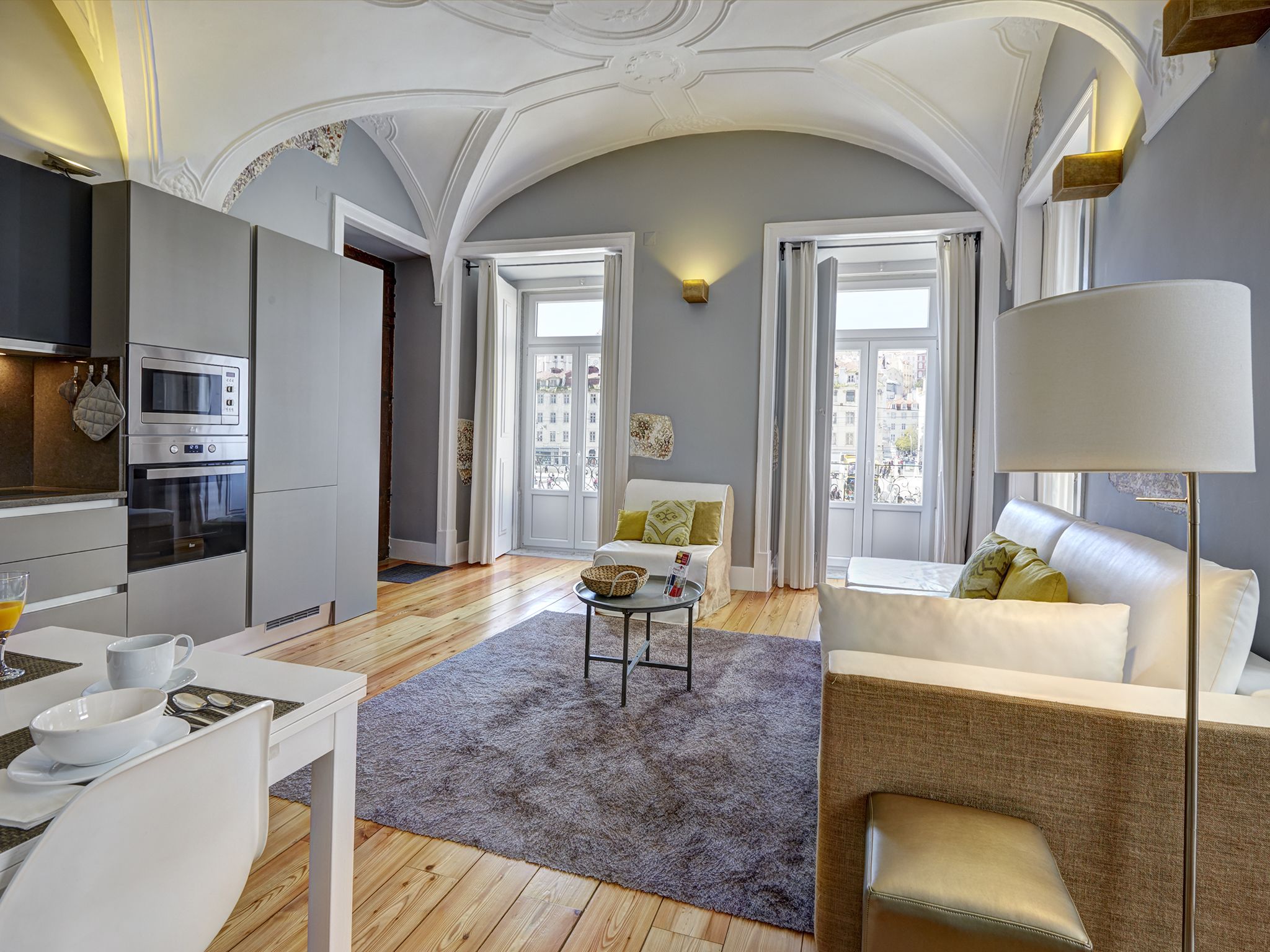 A modern living room with a sofa, a coffee table, and a dining area with a table and chairs.