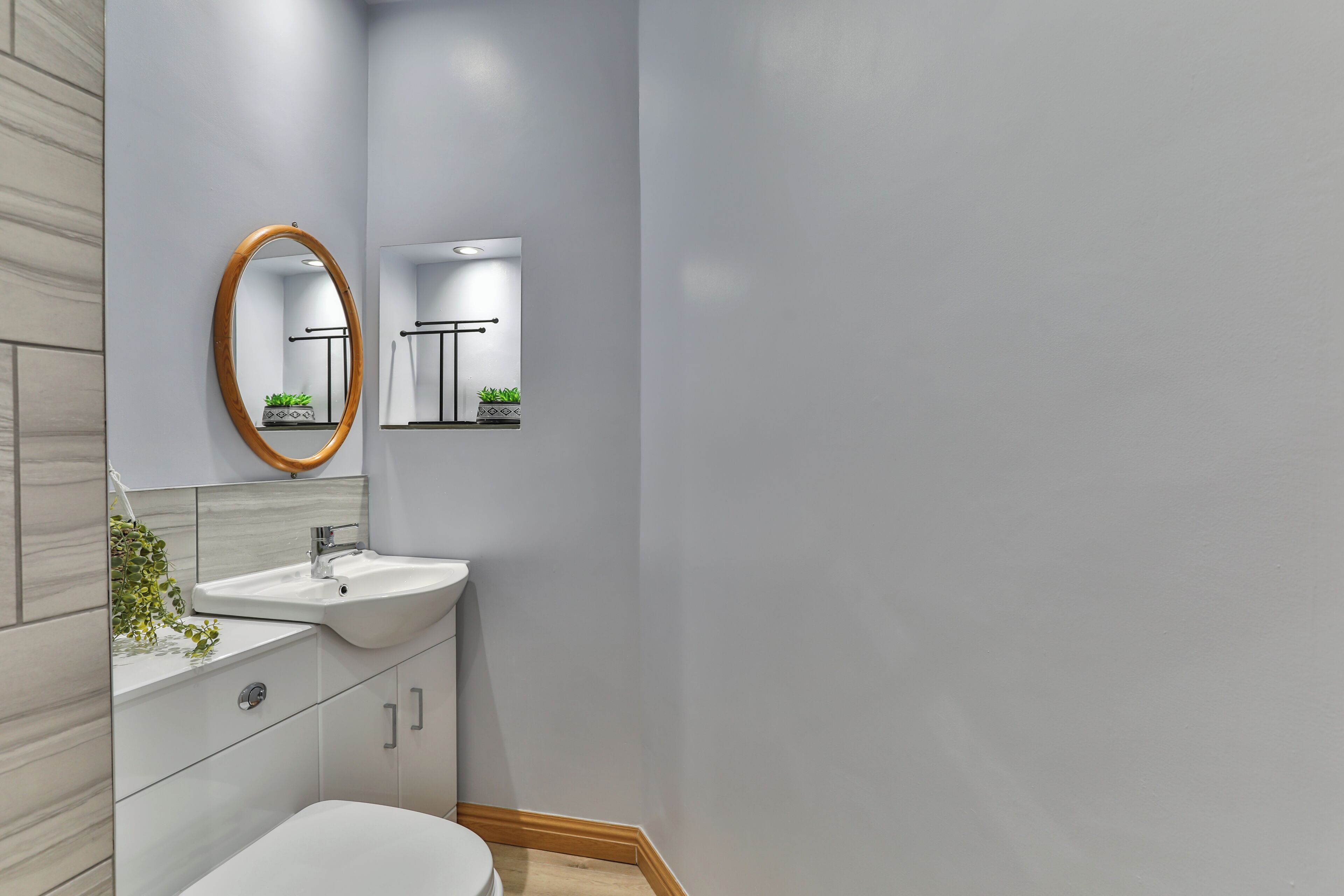 Une salle de bain moderne avec un lavabo blanc, un miroir et des toilettes.