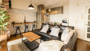 A compact living space with a sofa, coffee table, and a small kitchen area with a microwave and cabinets.