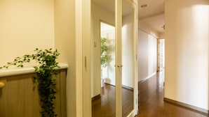 A hallway with wooden flooring, white walls, and a plant on the left.