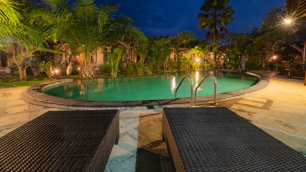 A swimming pool surrounded by palm trees and lounge chairs.