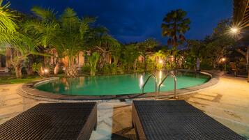 Una piscina al aire libre, sombrillas, sillones reclinables de piscina