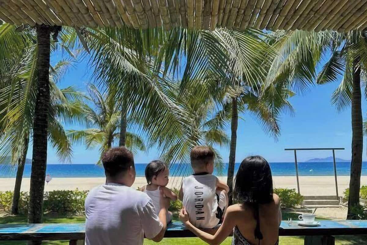 A covered outdoor area with a view of the beach and palm trees.